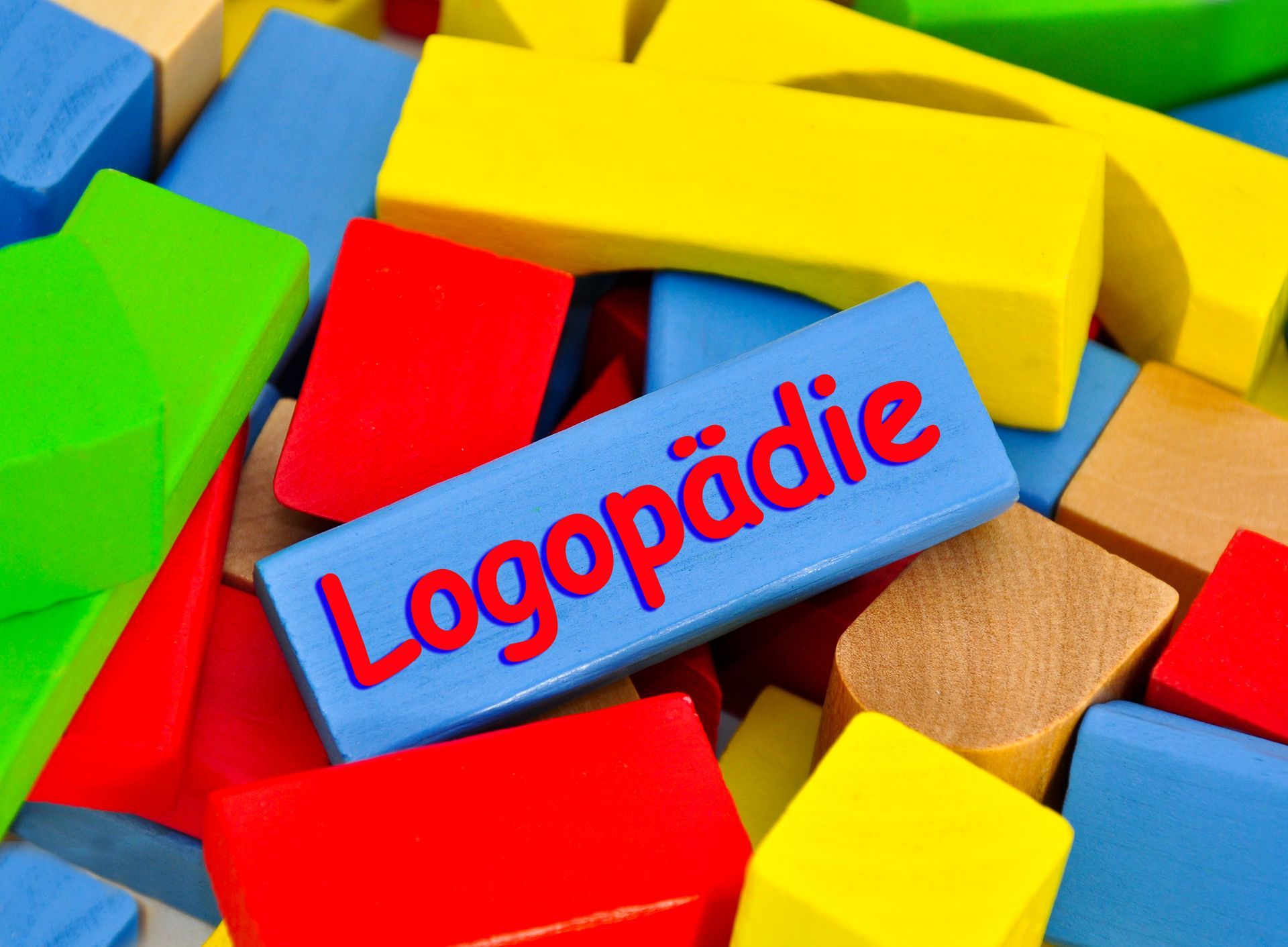 ein Stapel bunter Holzklötze mit einem blauen Block mit der Aufschrift „Logopädie“ darauf.