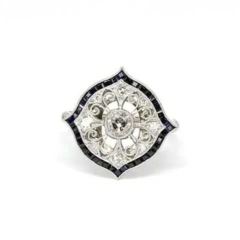 Un anillo de diamantes y zafiros en oro blanco sobre fondo blanco.