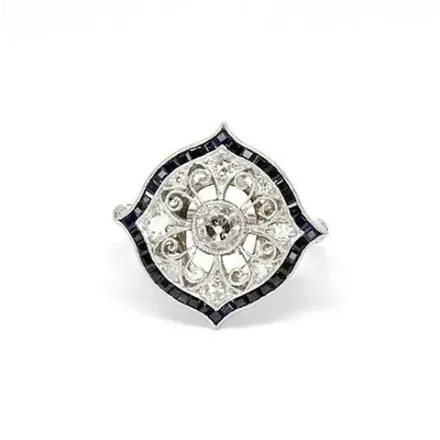 Un anillo de diamantes y zafiros en oro blanco sobre fondo blanco.