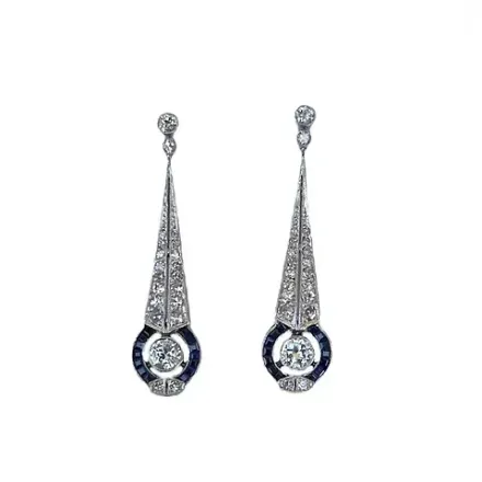 Un par de pendientes con diamantes y zafiros sobre fondo blanco.