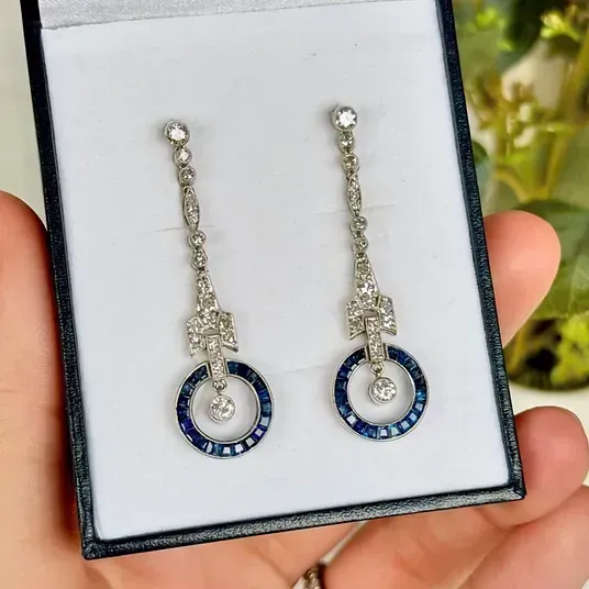 Una persona sostiene un par de pendientes en una caja.