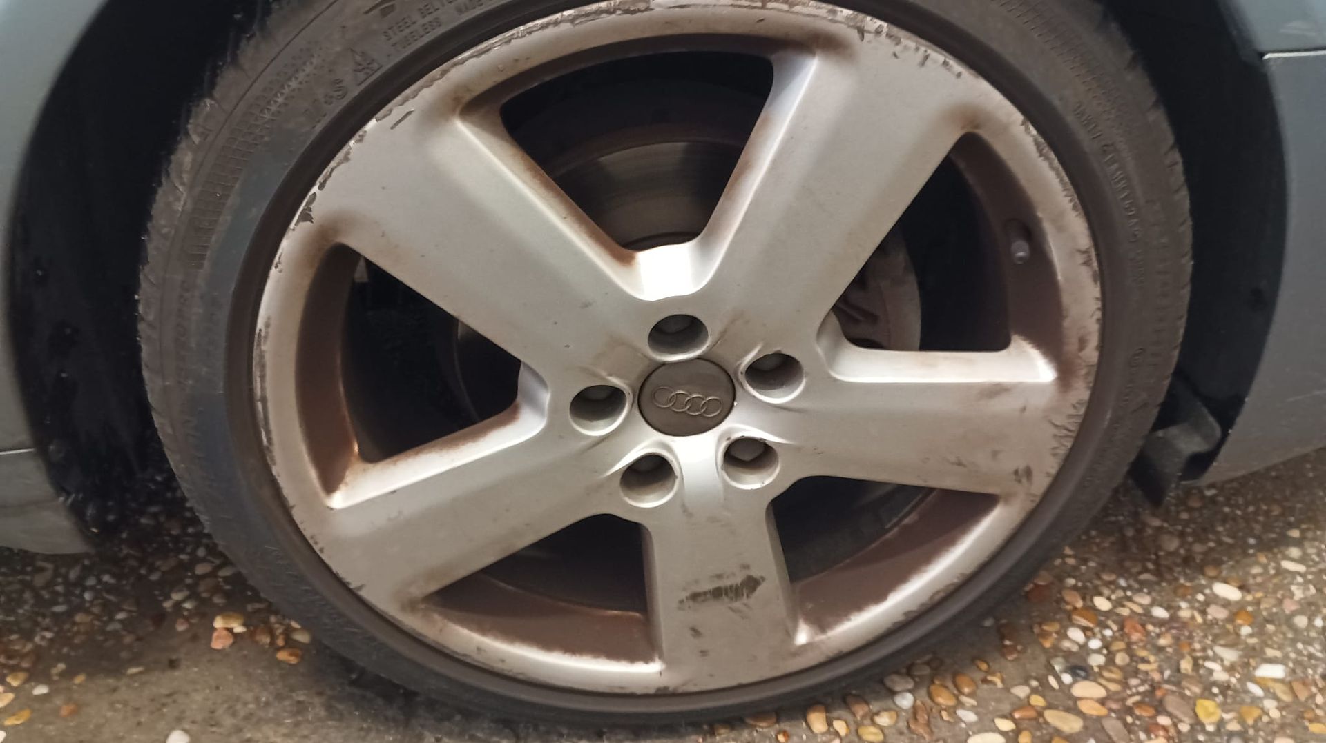 Un hombre está arreglando un disco de freno de un coche.