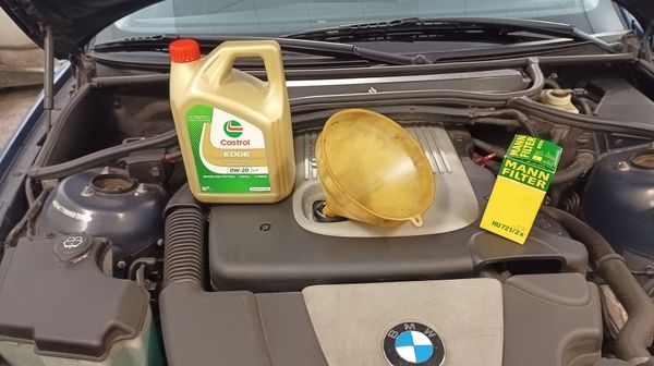 Un hombre está trabajando en el motor de un coche en un garaje.