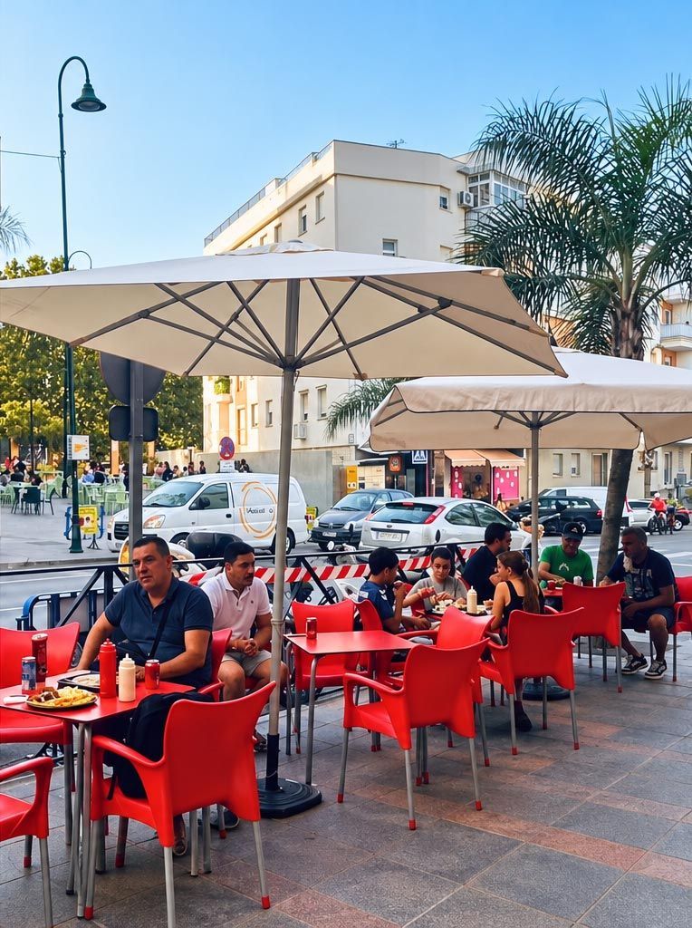 Café al aire libre con sillas rojas y sombrillas grandes en una terraza soleada a pie de calle