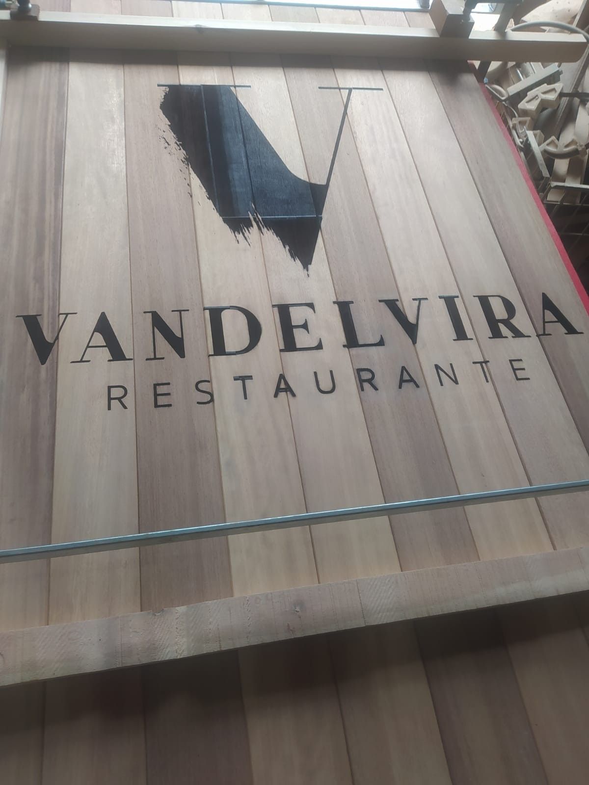 Un letrero de madera con un logotipo de pinceladas negras y el texto 