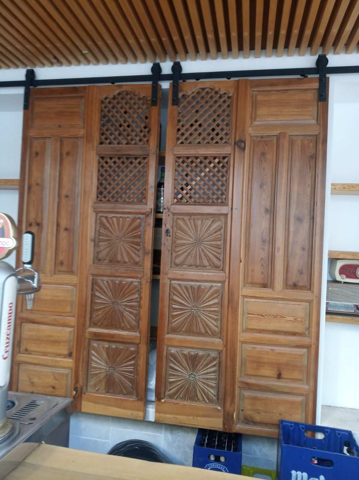 Dos puertas correderas rústicas de madera con celosía decorativa y paneles con estampado de estrellas, montadas sobre un riel negro.