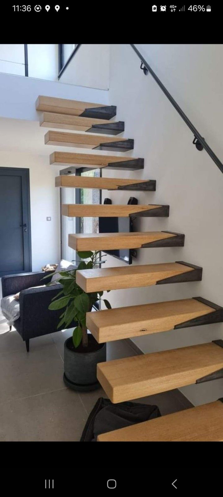 Escalera flotante de madera con soportes de metal negro fijados a una pared blanca en un espacio moderno.