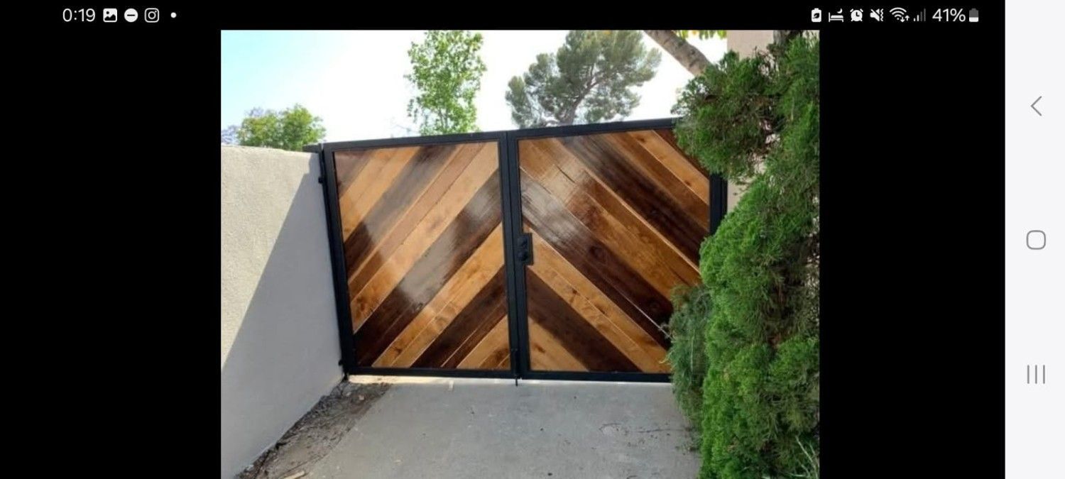 Una puerta de entrada doble con marcos de metal oscuro y tablones de madera claros y oscuros que contrastan, dispuestos en forma de espiga.