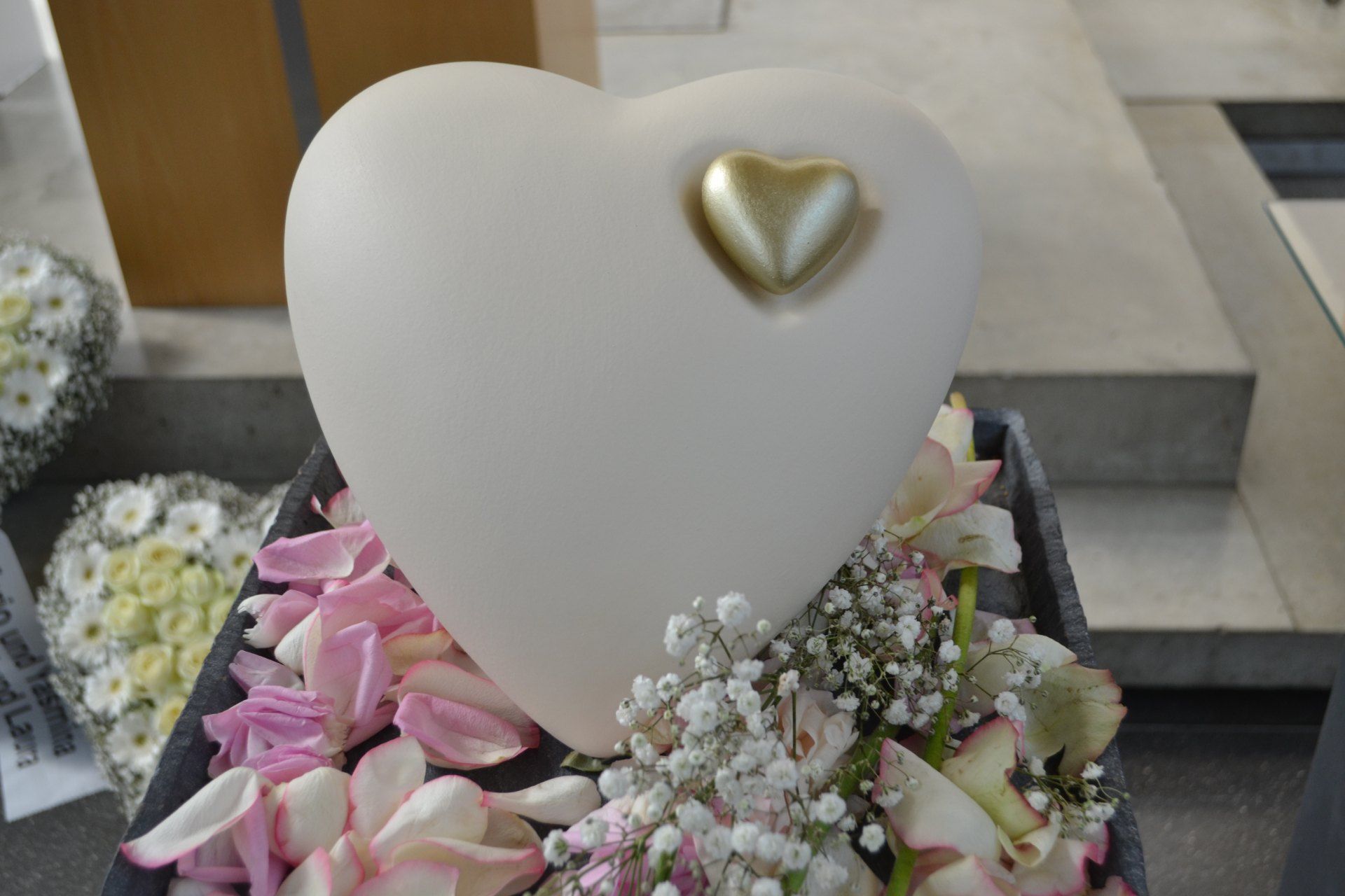 Weiße Urne in Herzform mit einem kleineren vergoldeten Herz 