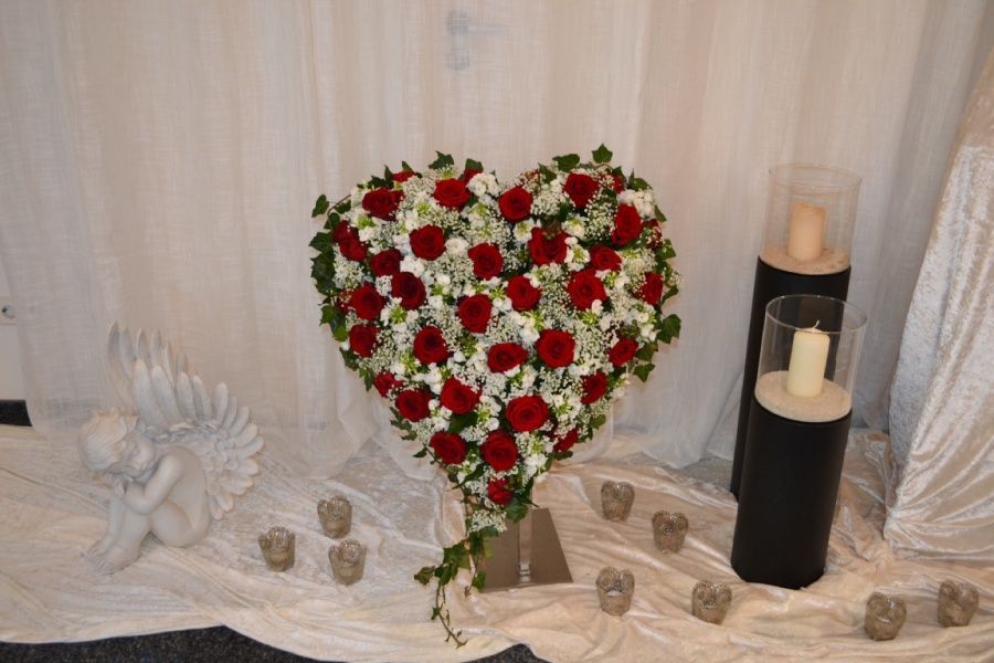 Aufgestelltes Blumengesteck in 3D-Herzform aus weißen und roten Rosen.