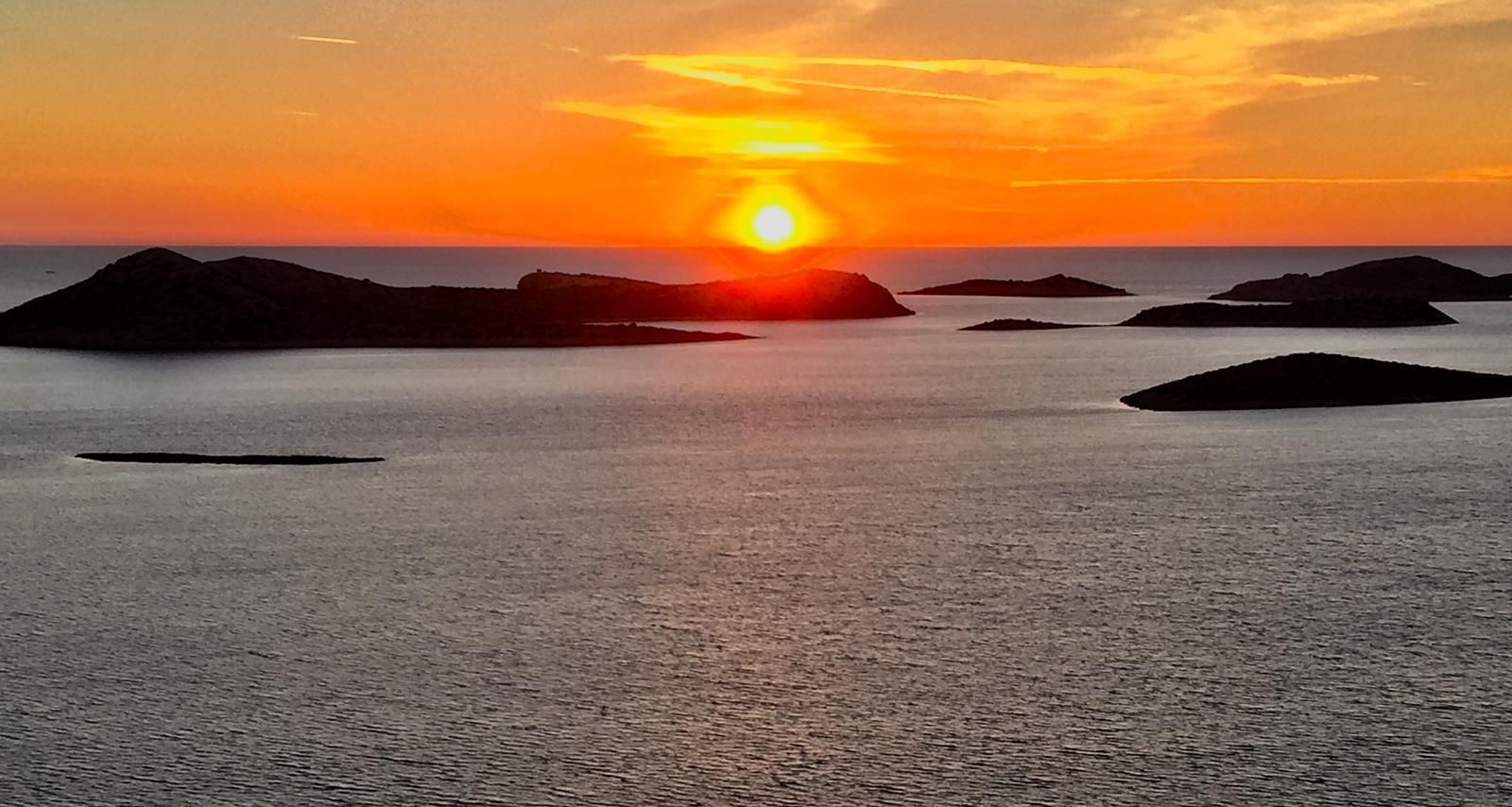 Ein Sonnenuntergang über einem Gewässer mit Inseln in der Ferne.