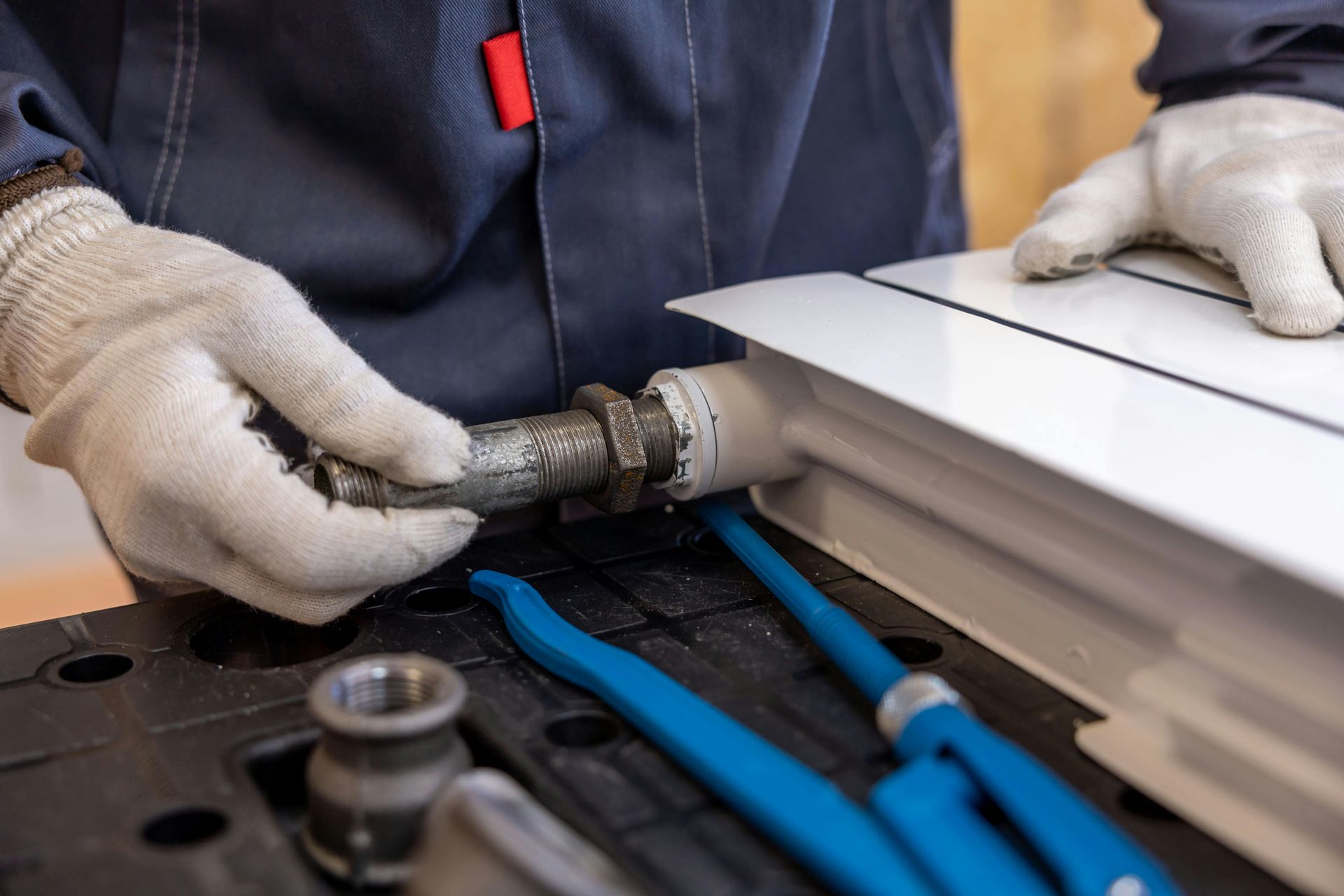Des mains gantées utilisent un outil électrique pour travailler sur le bord d'un toit blanc à côté d'outils bleus