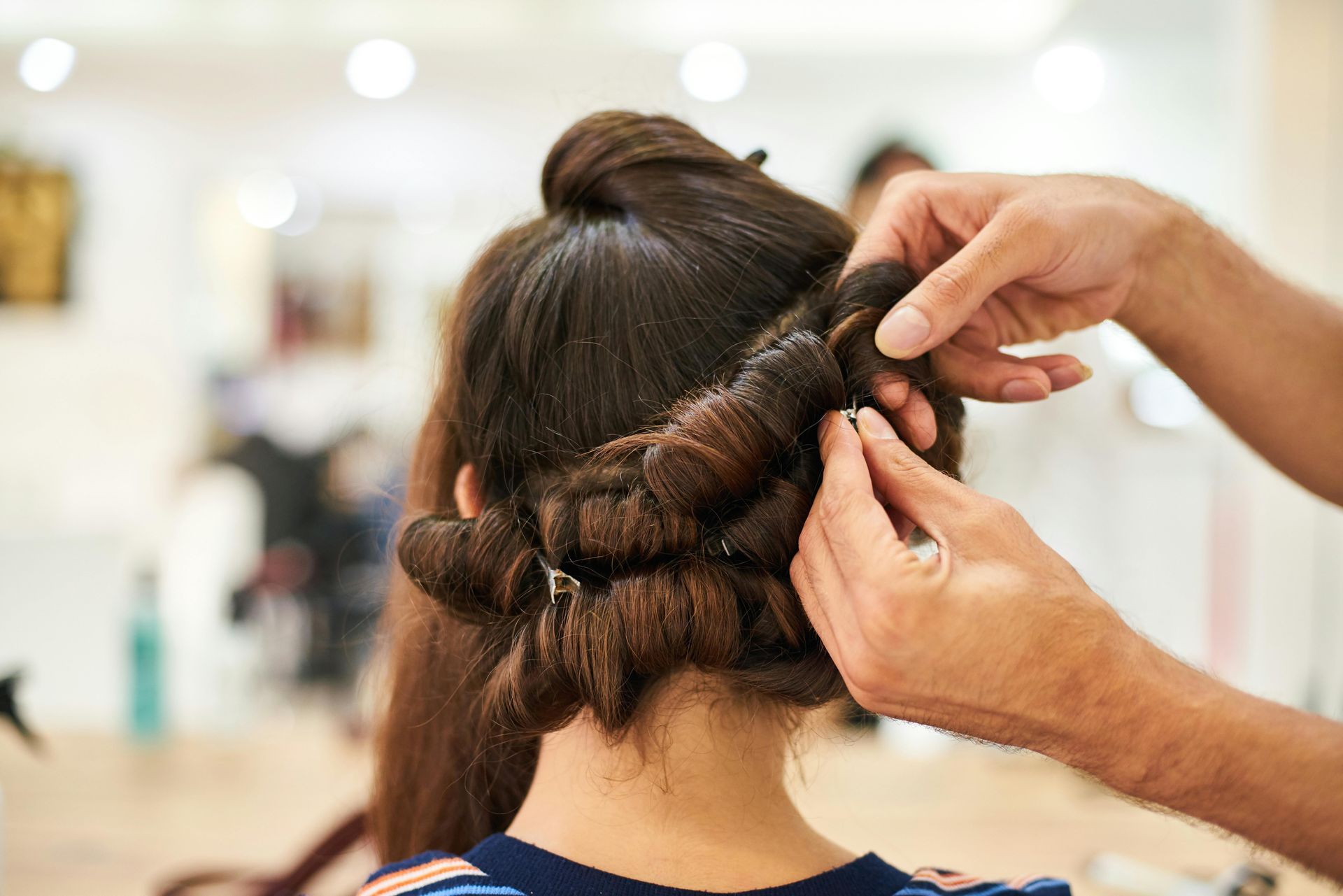 Coiffeuse réalisant une coiffure tressée foncée sur une cliente dans un salon