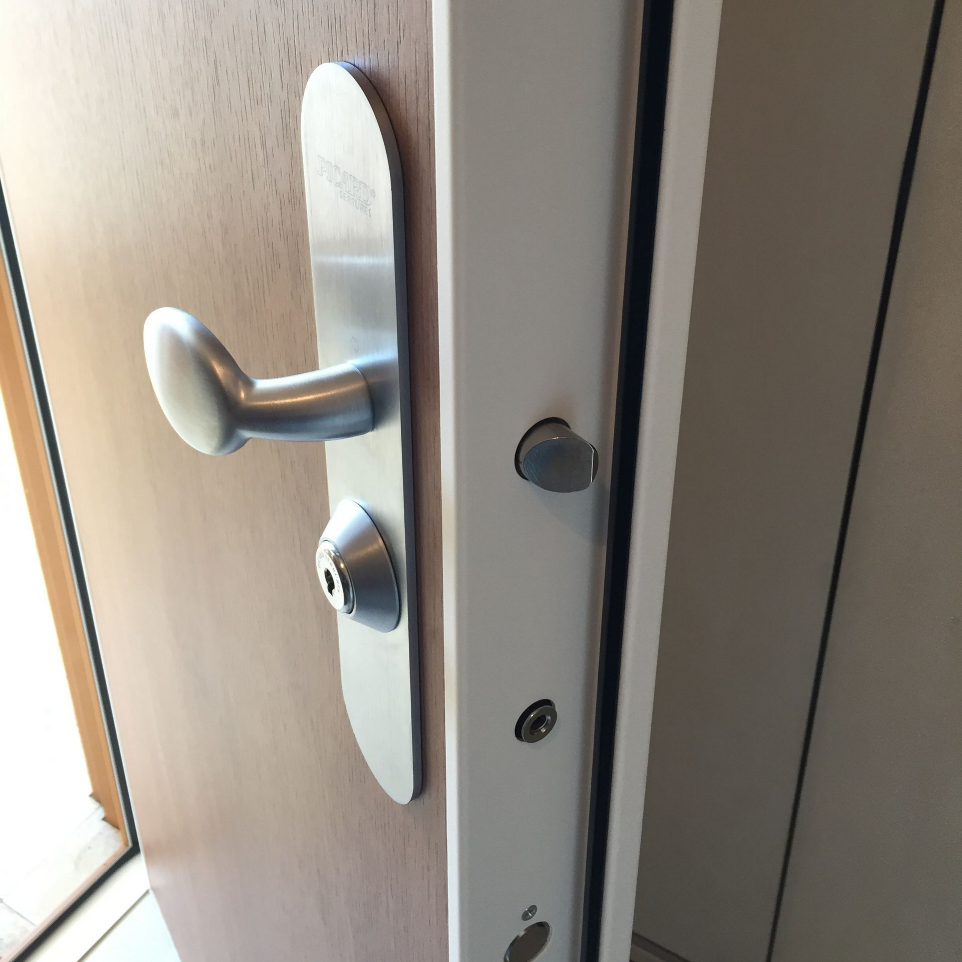Poignée de porte métallique sur une porte marron clair ouverte