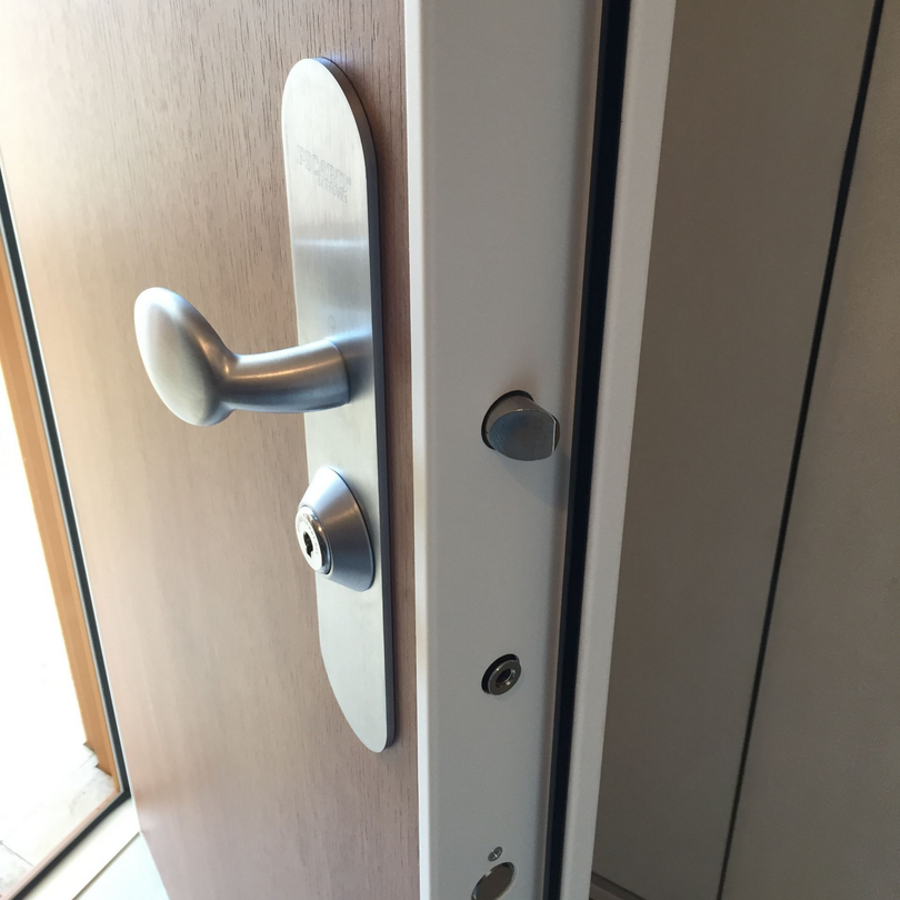 Poignée de porte métallique sur une porte marron clair ouverte