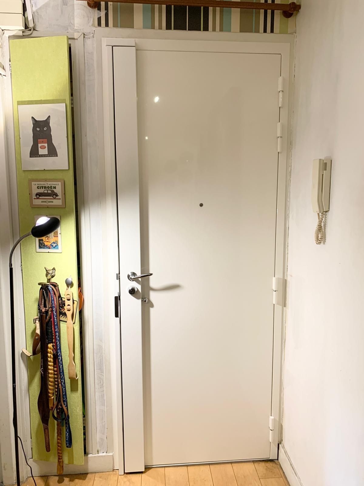 Porte intérieure blanche dans un couloir étroit avec des foulards suspendus et une décoration murale sur la gauche.
