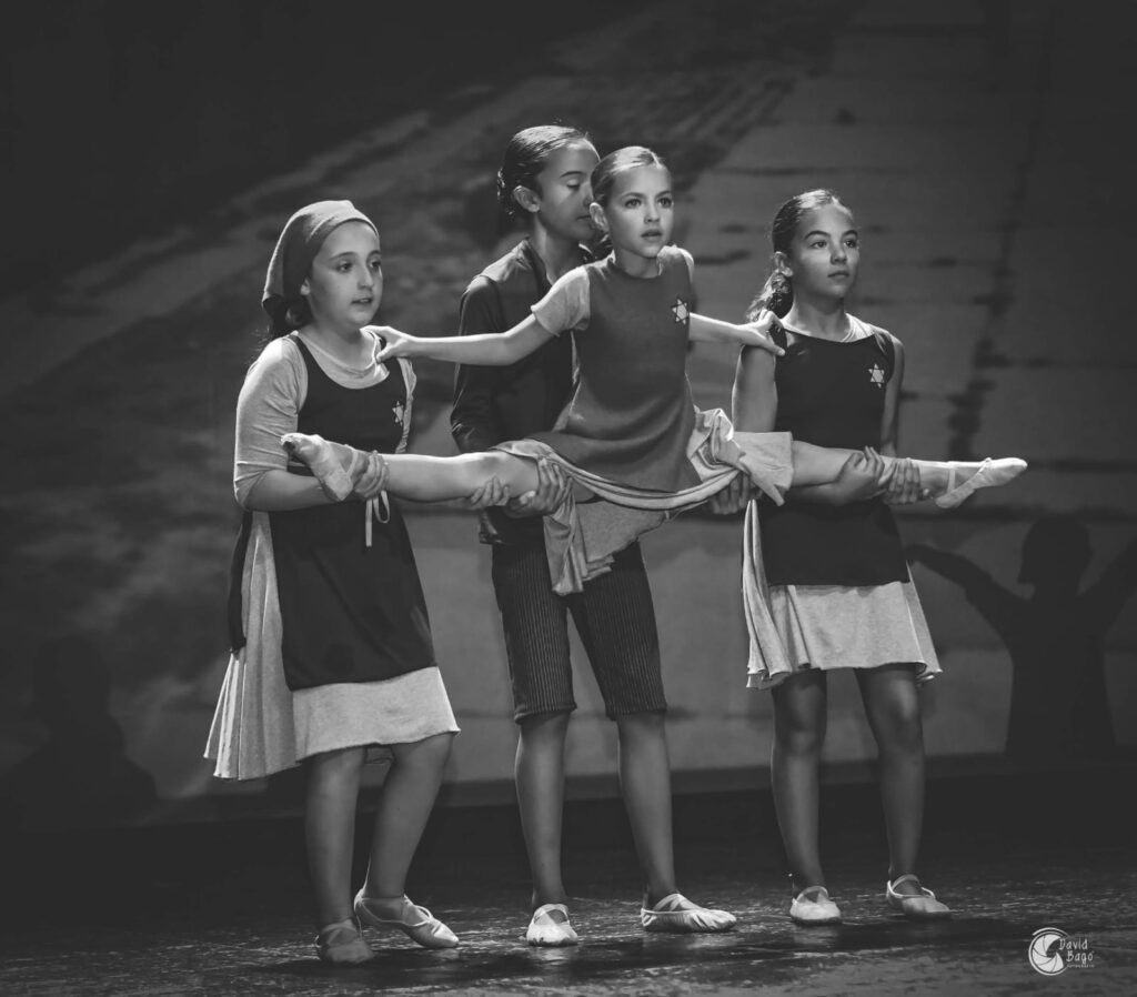 Un grupo de chicas jóvenes bailan en un escenario en una fotografía en blanco y negro.
