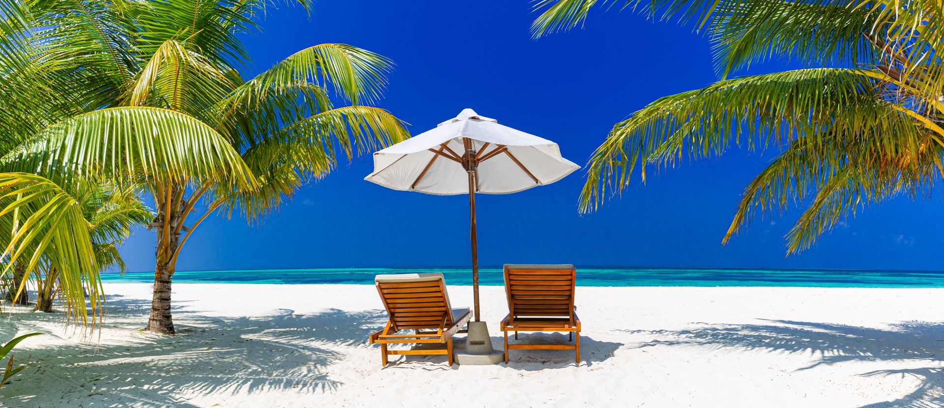 There are two chairs and an umbrella on the beach.