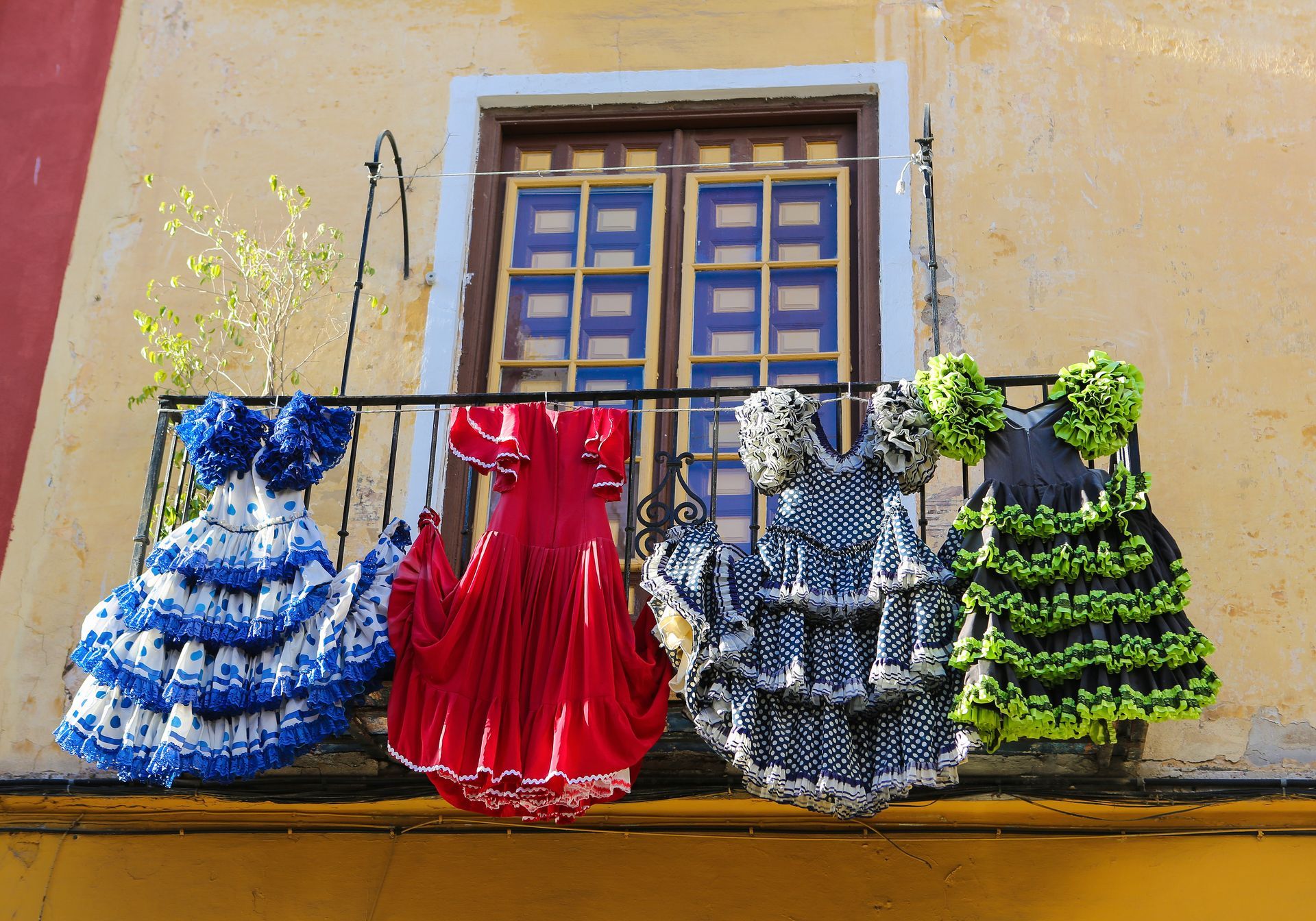 Three dresses are hanging on a balcony outside of a building