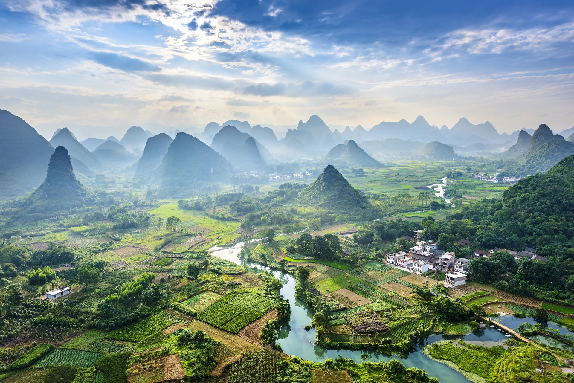 An aerial view of a river running through a lush green valley surrounded by mountains.