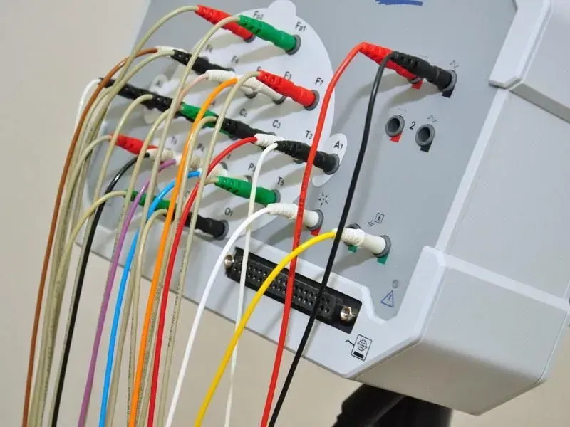 Nahaufnahme von farbigen Messleitungen, die an ein graues elektrisches Prüfpanel angeschlossen sind.