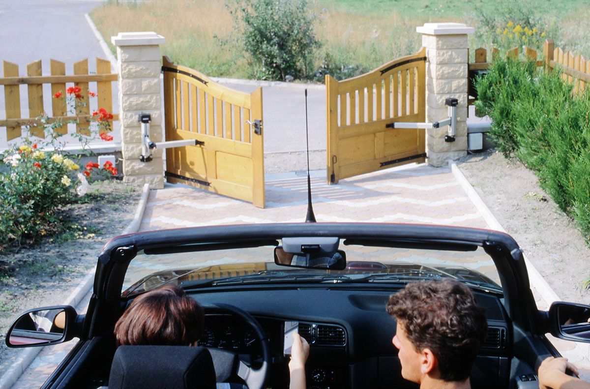 Couple en voiture qui ouvre un portail avec un portable