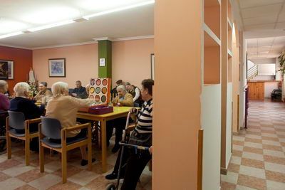 Un grupo de personas mayores están sentadas en mesas en una habitación.