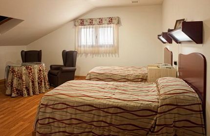 Un dormitorio con dos camas, una mesa y sillas.