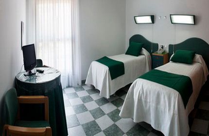 Una habitación de hotel con dos camas y una mesa con una computadora encima.