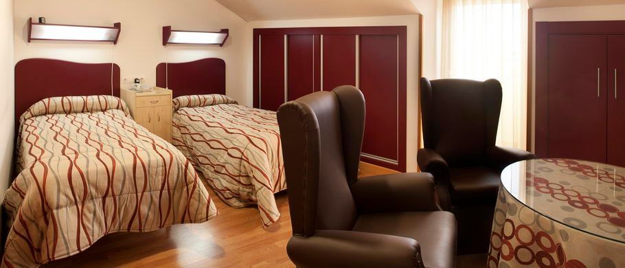 Un dormitorio con dos camas, una silla y una mesa.