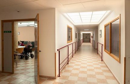 Un largo pasillo en un hospital con un hombre en silla de ruedas.