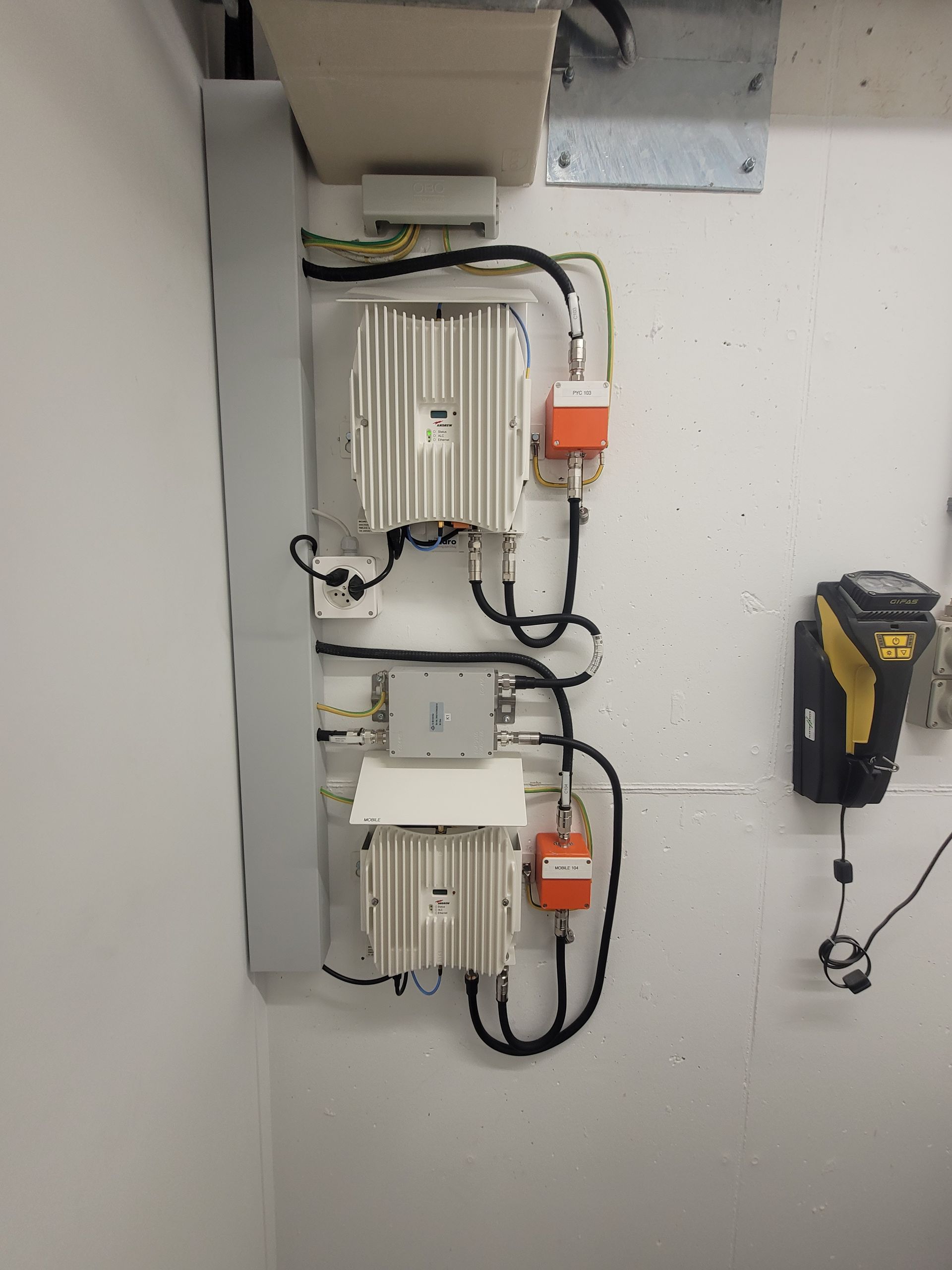 Zwei hohe Antennen auf einem Dach mit Blick auf die Stadtlandschaft bei bewölktem Himmel.