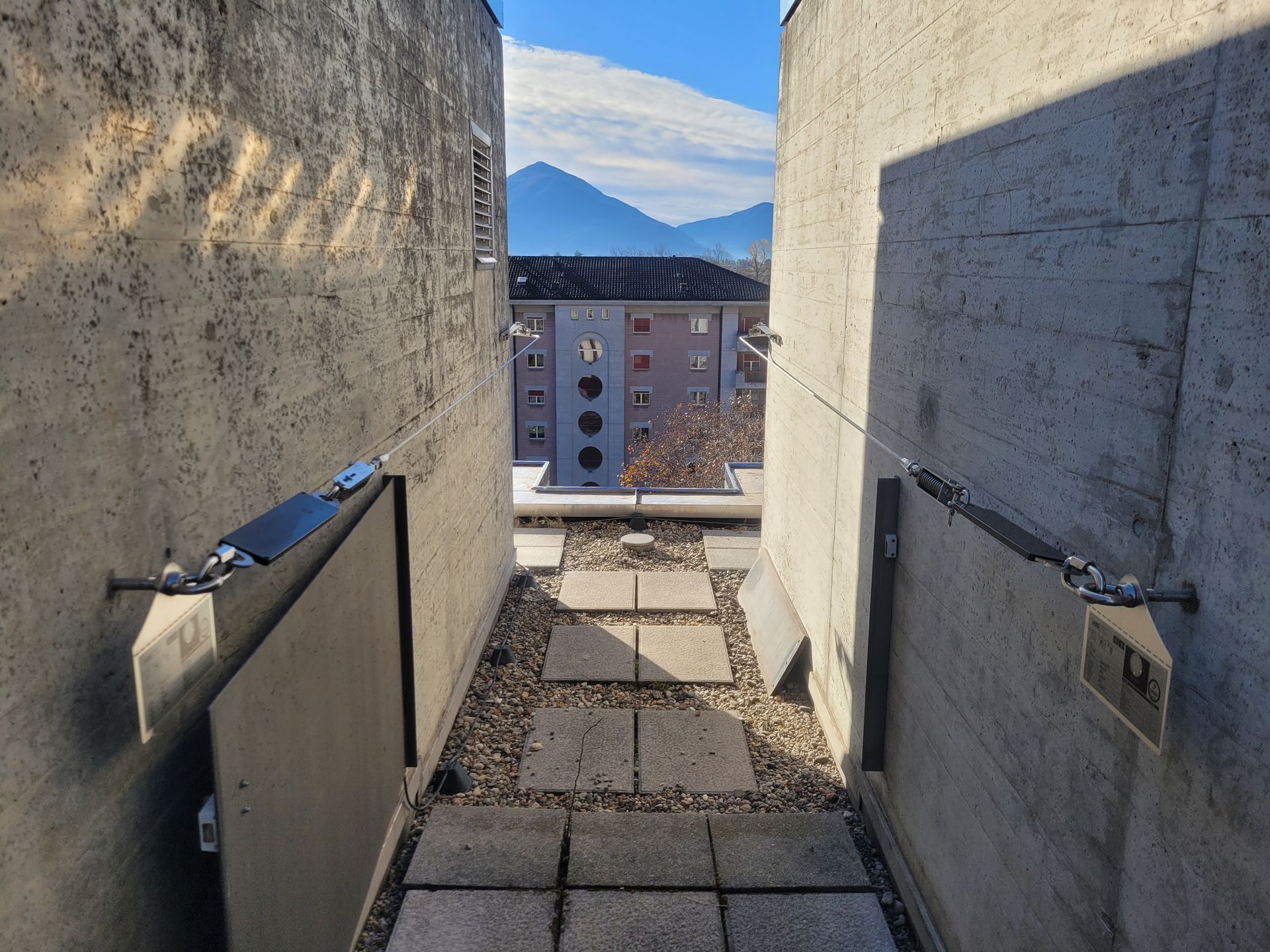Elektrische Leitungen und Kabel an der Decke, mit einem gebogenen schwarzen Rohr und einem Strahler.