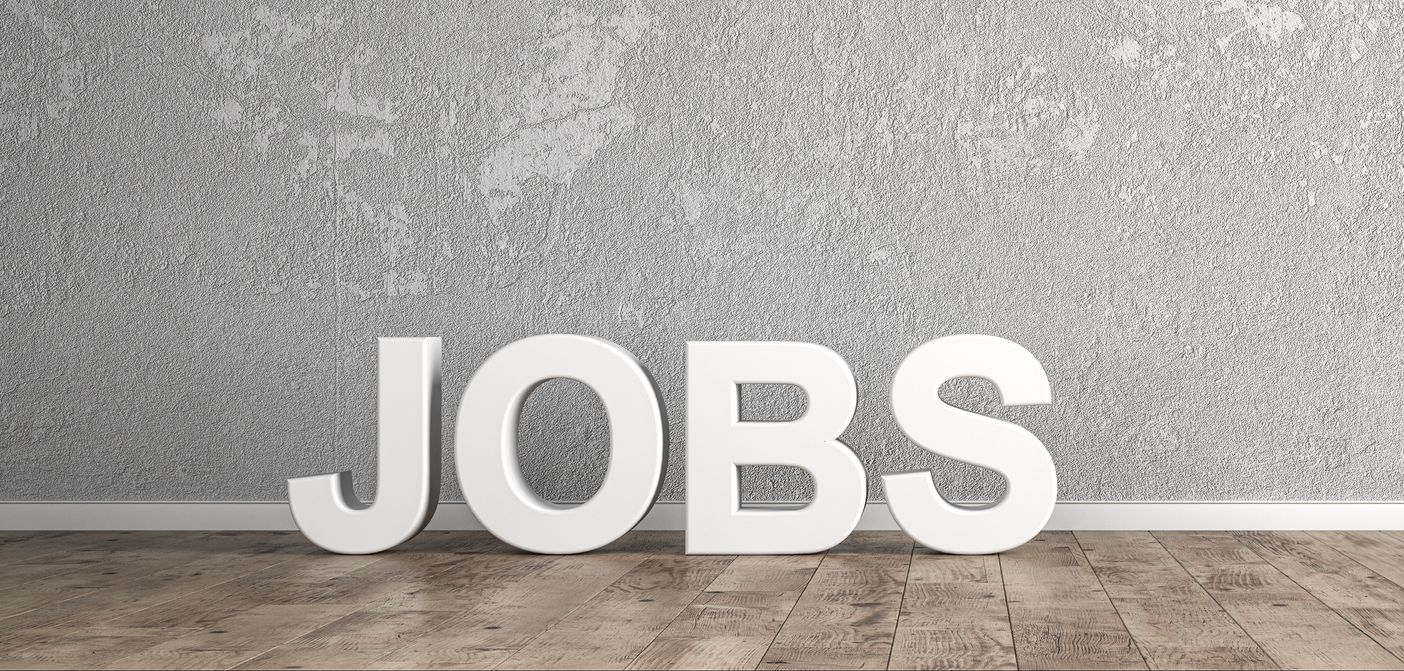 Eine Frau und ein Mann im Anzug unterhalten sich an einem Schreibtisch in einem Büro.