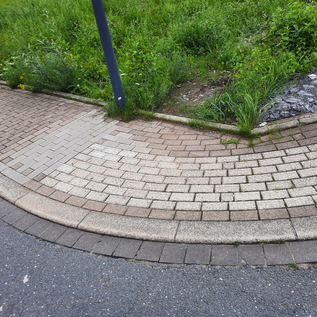 Ein gepflasterter Gehweg mit einer Rasenfläche im Hintergrund