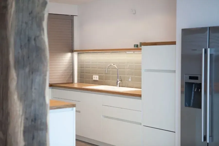 Eine Küche mit weißen Schränken, einer Spüle und einem Kühlschrank.