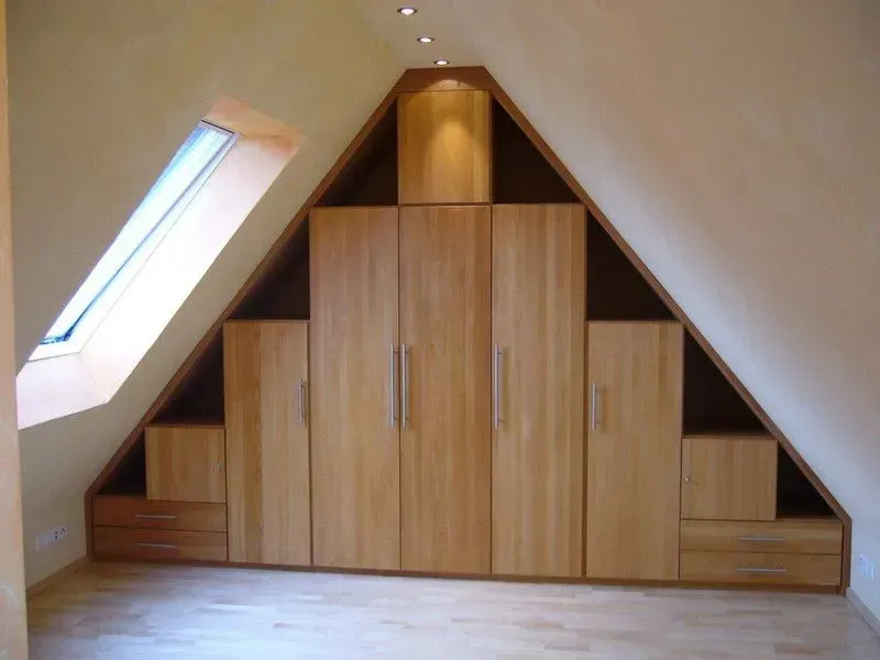 Ein Zimmer mit einem dreieckigen Kleiderschrank und einem Fenster