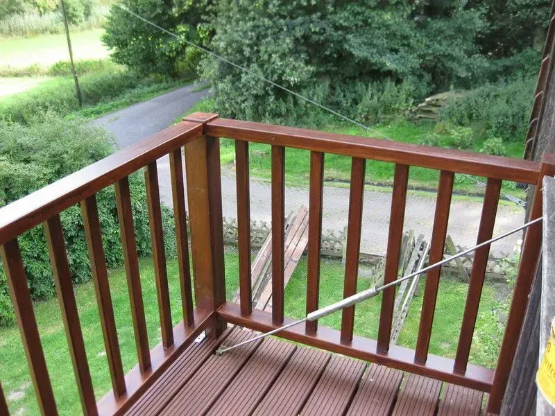 Ein Balkon mit einem Holzgeländer mit Blick auf ein üppiges grünes Feld
