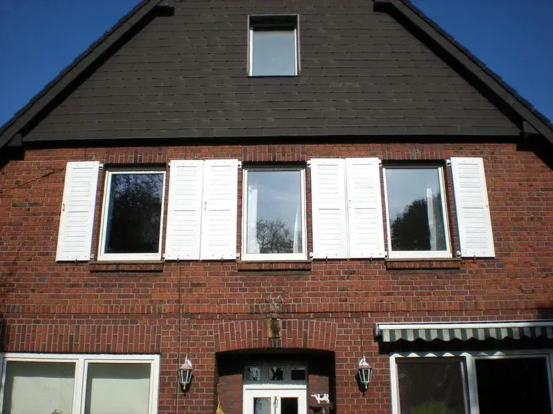 Ein rotes Backsteinhaus mit weißen Fensterläden