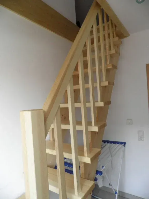 Eine Holztreppe in einem Raum mit einer weißen Wand