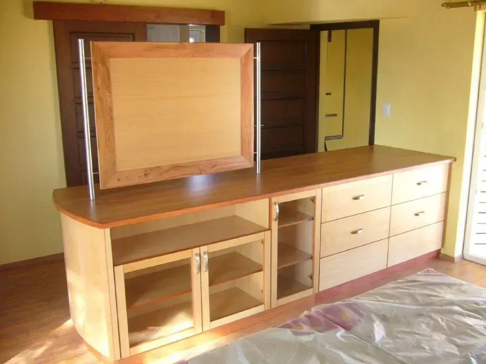 Ein Holzschrank mit Schubladen und Regalen in einem Zimmer