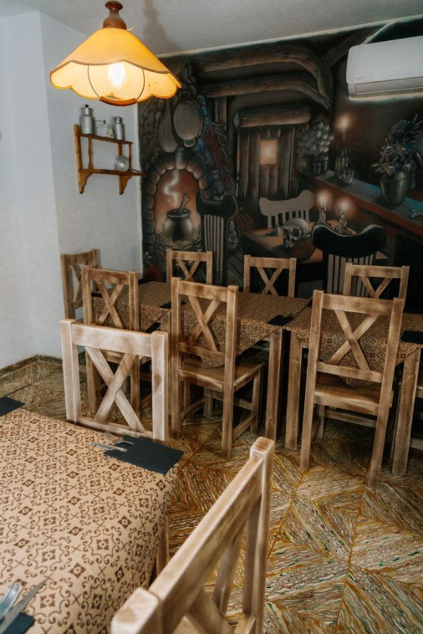Acogedor comedor rústico con sillas de madera, manteles estampados y una pared con chimenea mural.