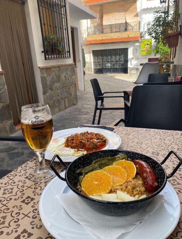 Cerveza y un desayuno a la sartén en una mesa en la terraza de una cafetería al aire libre.