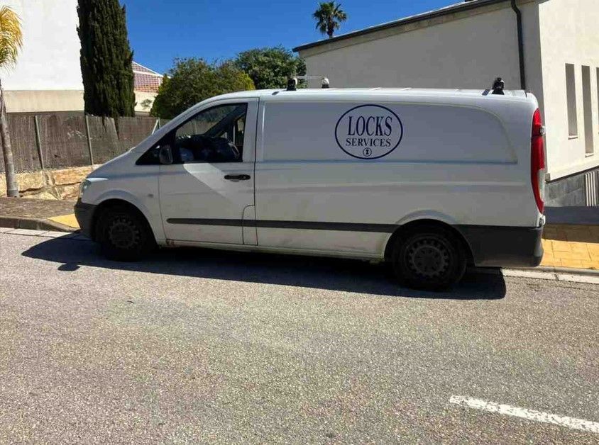 Una furgoneta comercial blanca aparcada en una calle asfaltada, con el logotipo