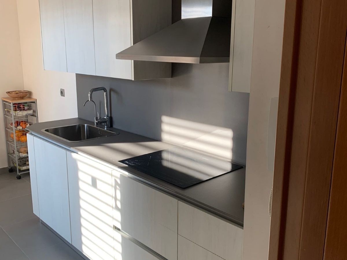 Una cocina con gabinetes blancos, un fregadero y un horno de estufa.