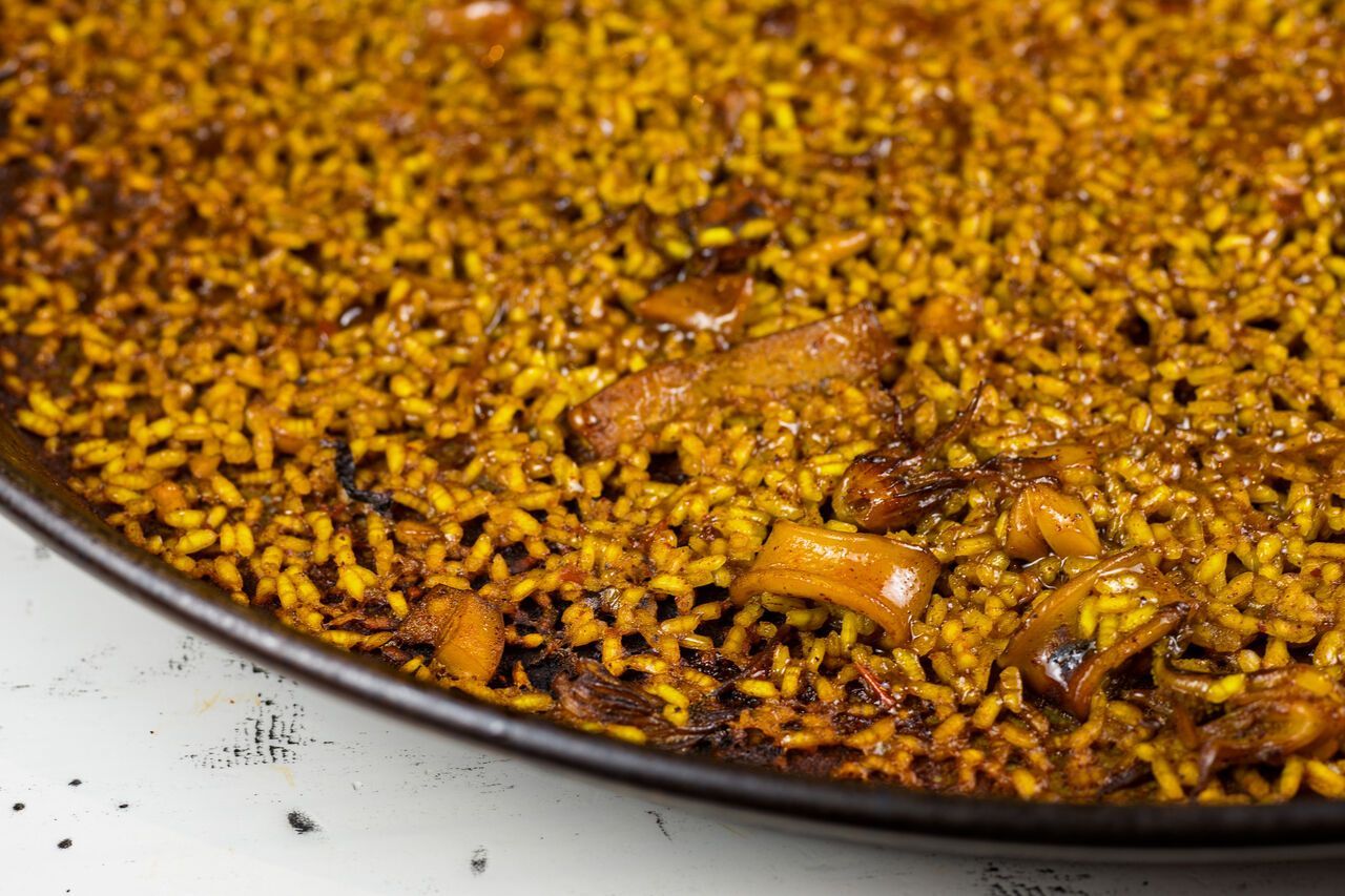 Primer plano de una sartén llena de arroz dorado y verduras, con trocitos caramelizados en la superficie.
