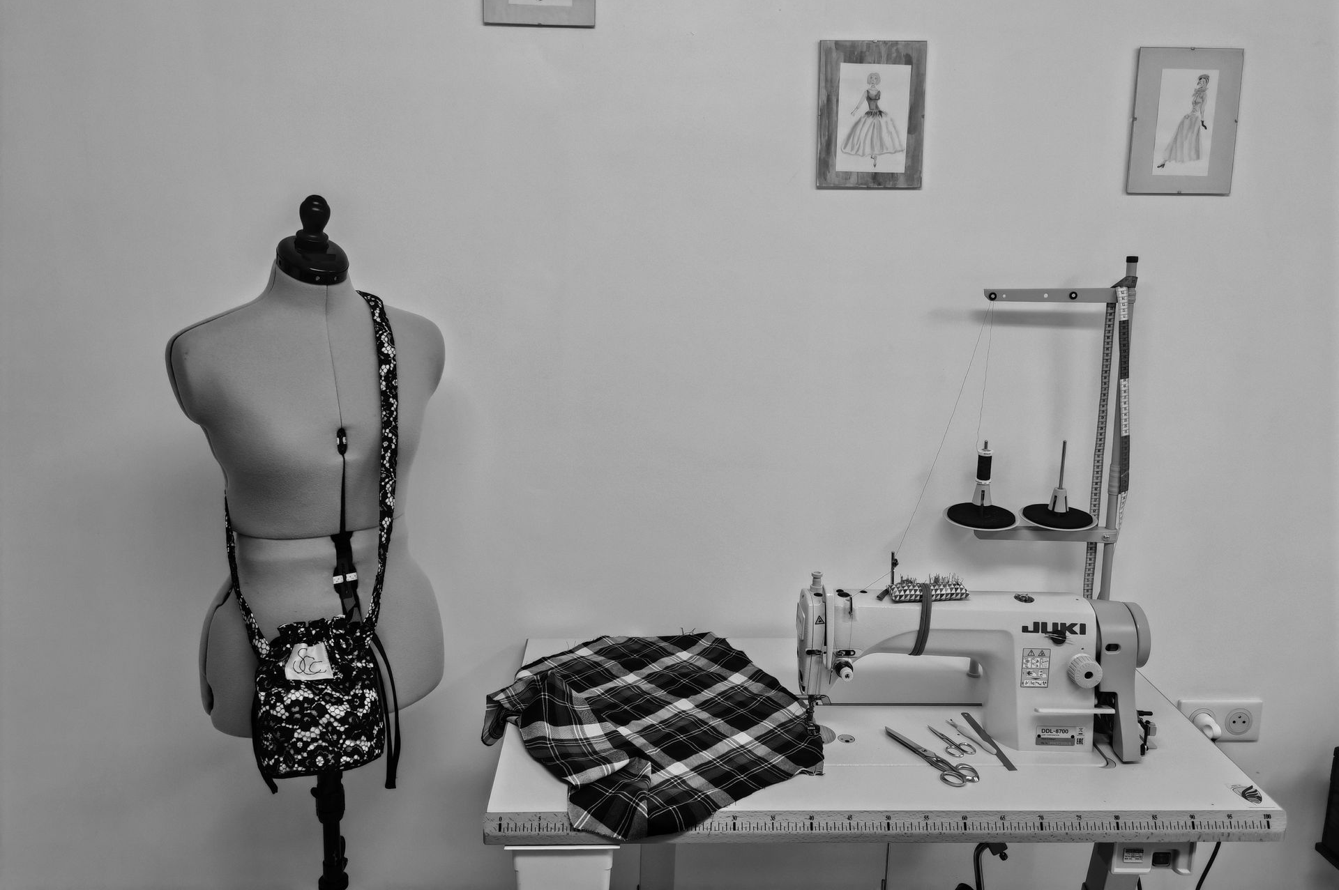 Atelier de couture avec mannequin de couture, machine à coudre et tissu plié sur une table de travail.