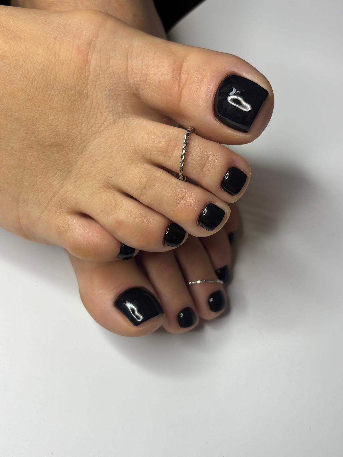 Primer plano de pies con esmalte de uñas rosa sobre una superficie de piedra.