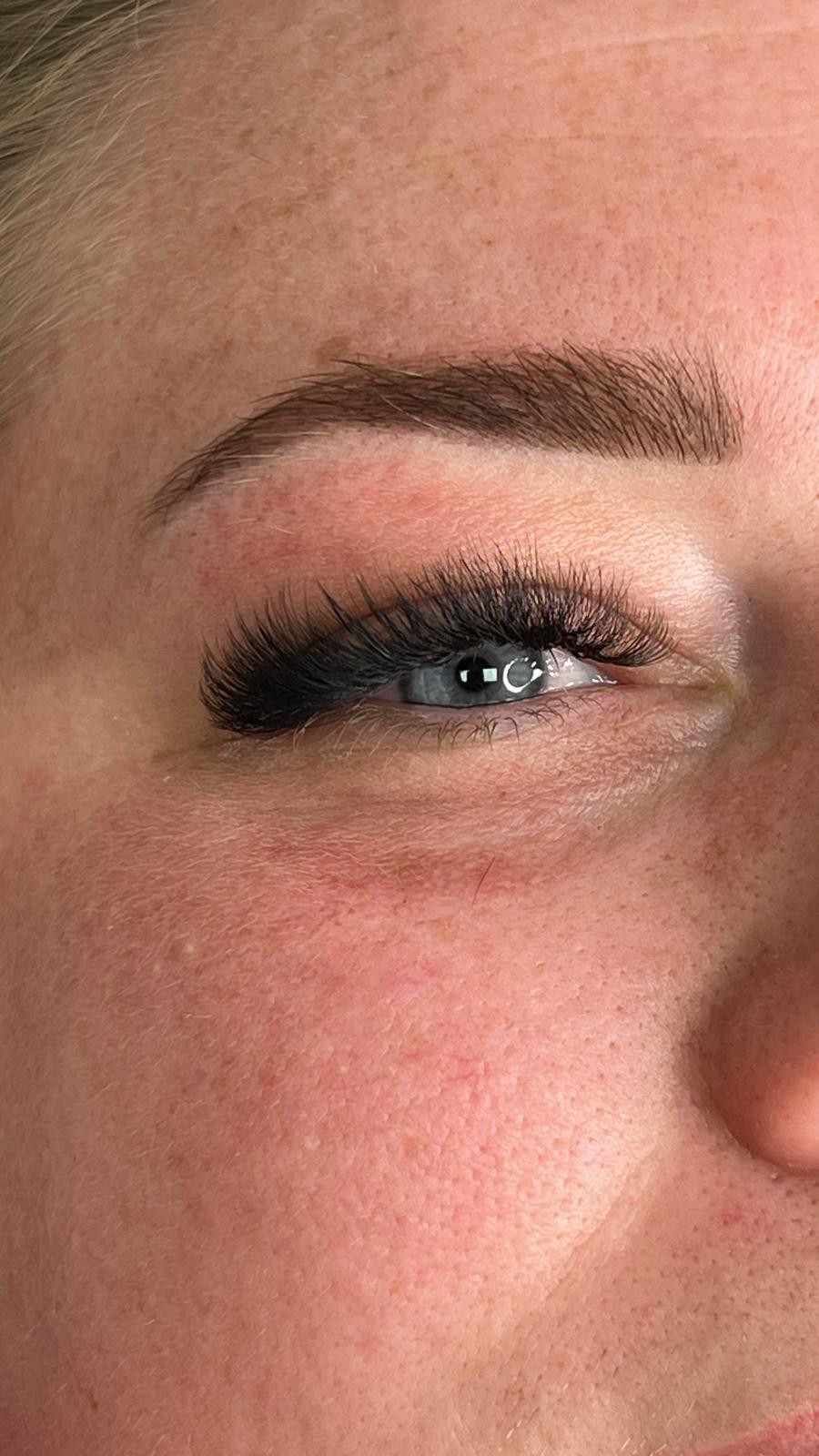 Primer plano de un ojo sonriente con maquillaje azul y una ceja bien definida.