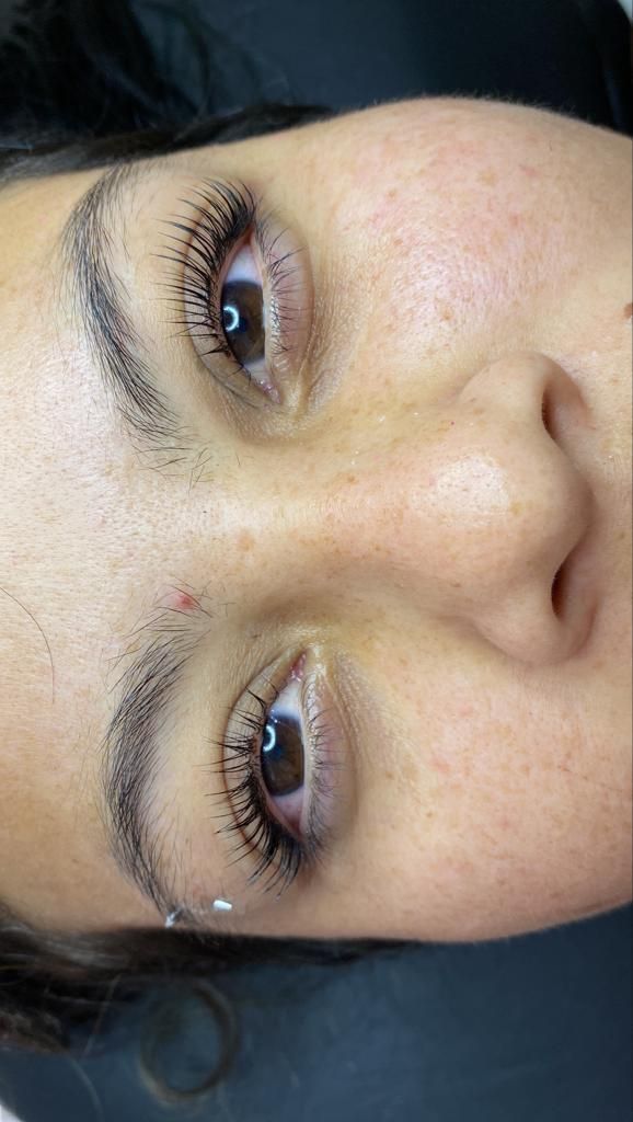 Primer plano de un rostro con cabello oscuro, pecas y maquillaje blanco brillante cerca de los ojos.